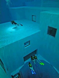 two scuba divers are swimming in the blue water inside an underwater room that is lit up