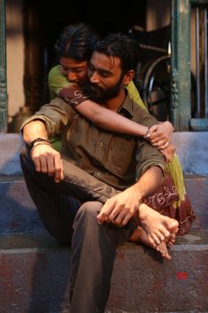 two men sitting on the steps hugging each other