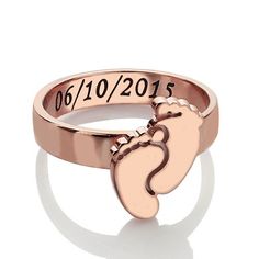 a rose gold ring with a baby's footprints and date on the front side