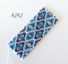 a blue and white beaded bracelet sitting on top of a piece of paper next to a pair of scissors