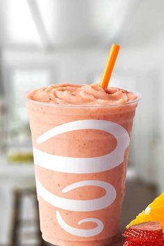 a smoothie with strawberries and orange slices on the side