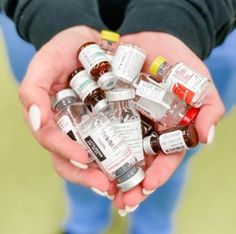 a person holding many medicine bottles in their hands