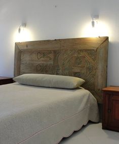 a bed with two lamps on either side of it and a wooden headboard in the middle