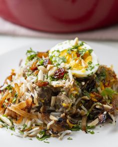 a white plate topped with rice and meat covered in an egg on top of broccoli