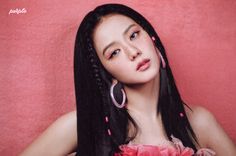 a woman with long black hair and pink dress posing for a photo in front of a red wall