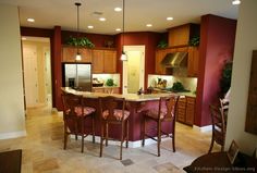 a large kitchen with wooden cabinets and marble counter tops, along with bar stools