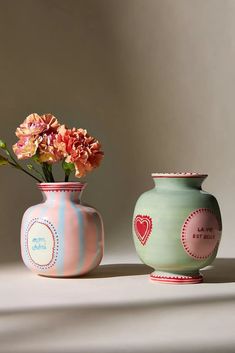 two vases with flowers in them sitting on a table next to each other,