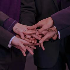 several people in suits and ties stacking their hands together