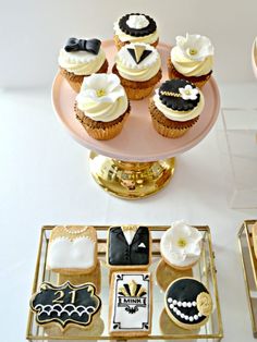 an assortment of decorated cupcakes sitting on top of a cake plate next to other dessert items