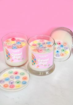 three candles with buttons in them sitting on a table next to a container of candy