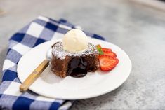 a piece of chocolate cake on a plate with ice cream and strawberries