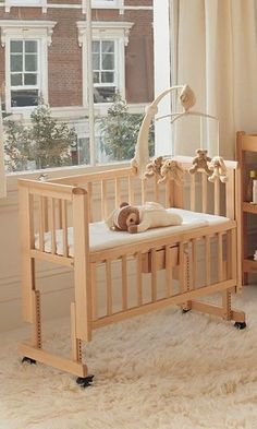 a baby crib in front of a window with a teddy bear on the bed