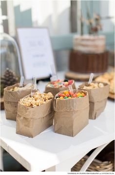 small brown paper bags filled with food on top of a white table next to other items