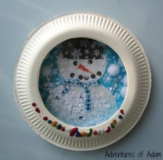 a paper plate snow globe with a snowman on it