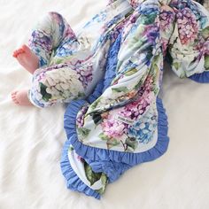 a baby is laying on the bed wearing a flowery blanket and blue ruffled diaper