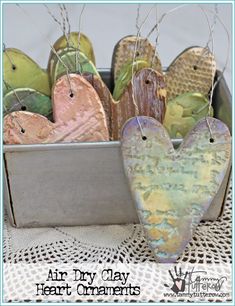 some heart shaped ornaments are in a metal box on a doily tablecloth with the words, air dry clay heart ornaments