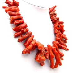 an orange necklace is displayed on a mannequin's neckline, with several pieces of red coral in the shape of elephants