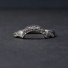 a white gold ring with three diamonds on the top and bottom, sitting on a black surface