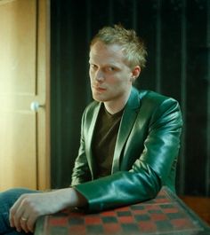 a man sitting at a table wearing a green jacket