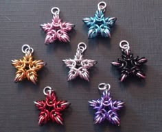 six different colors of metal charms on a table with one charm in the shape of a snowflake