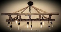 a light fixture made out of wooden beams with bulbs hanging from the ceiling and some lights on