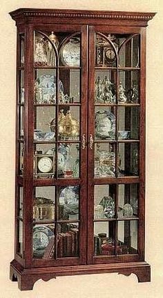 an antique china cabinet with glass doors and shelves