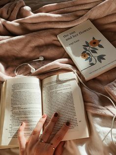 a person reading a book on top of a bed next to an earbud