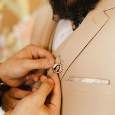 a man adjusting the collar of another mans suit