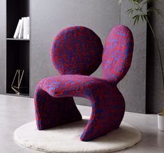 a red and blue chair sitting on top of a white rug next to a book shelf