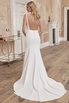 a woman in a white wedding dress standing on a wooden floor with her back to the camera