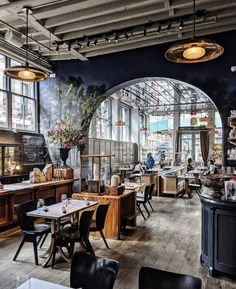 the interior of a restaurant with many tables and chairs in front of large arched windows