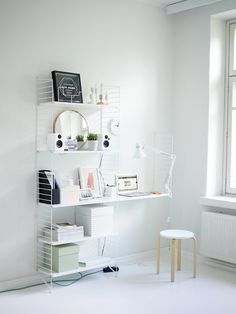 a white room with a desk, chair and mirror on the wall next to a window