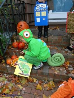 a small child dressed as a chamelon sitting on the steps