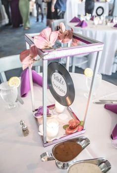 the table is set up for a wedding reception with purple and white decorations on it