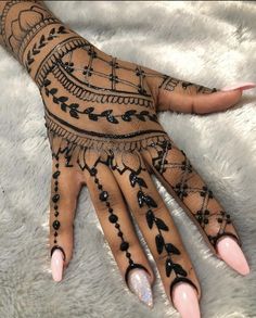 a woman's hand with black and white henna tattoos on her left arm