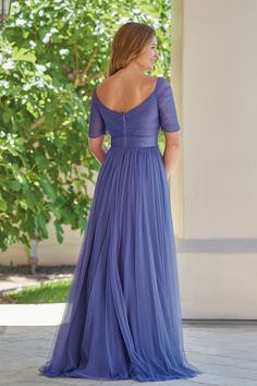 a woman in a long blue dress looking off to the side with her back turned