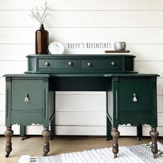 a green desk with two drawers and a clock sitting on it's top shelf