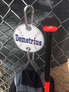 there is a baseball and bat hanging from a chain link fence with the name demeterius on it