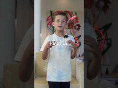 a young boy standing in front of a mirror holding a toothbrush and looking at the camera