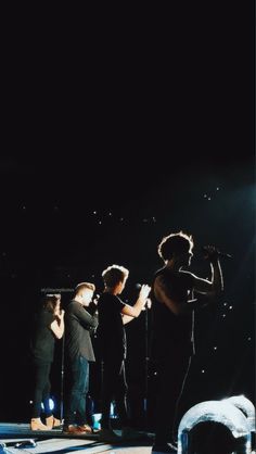 three people standing on stage with microphones in front of them and one person holding something up