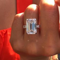 a close up of a person holding a ring with a large diamond in the middle