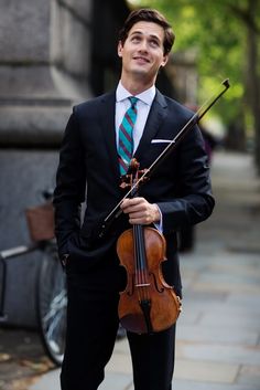 a man in a suit and tie holding a violin