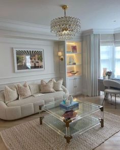 a living room filled with furniture and a chandelier above a glass coffee table