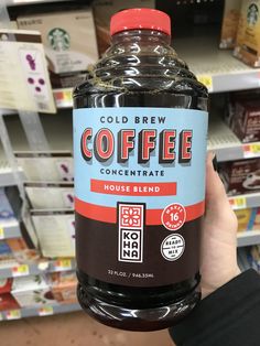 a person holding up a bottle of coffee