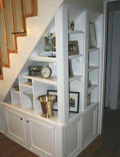 an open bookcase under the stairs in a house