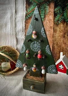 a small christmas tree with ornaments hanging from it's sides on a wooden stand