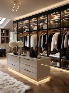 a large walk in closet with lots of clothes on shelves and lighting under the lights