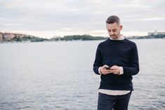 a man standing by the water looking at his cell phone