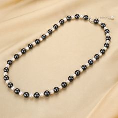 This black and white pearl beaded necklace is a stunning fusion of black and white pearls. This exquisite beaded necklace features a captivating centerpiece: a large 10-11mm colored black pearl, radiating elegance and allure. The sleek and lustrous black pearl is delicately complemented by smaller 6-7mm white freshwater pearls, adding a touch of contrast and sophistication. Crafted with meticulous attention to detail, this necklace exudes a harmonious blend of opulence and refinement. Designed f Elegant Black Beaded Necklaces, Elegant Black Beaded Pearl Necklace, Silver Pearl Necklace With Black Round Beads, Elegant Black Pearl Necklace, Elegant Black Bead Necklaces For Gift, Elegant Black Beads Necklace For Gift, Black Beaded Pearl Necklaces With Pearl Pendant, Black Beaded Necklace With Pearl Pendant, Black Beaded Necklaces With Pearl Pendant