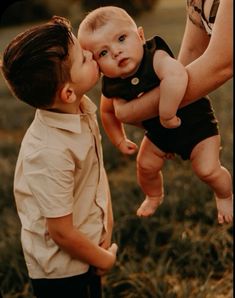 a man holding a baby up to his face as he kisses it's cheek